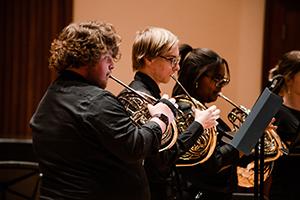 三个学生演奏铜管乐器.