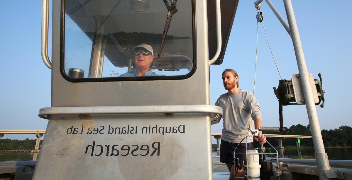 Dr. 约翰Lehrter, 海洋科学副教授, 驾驶船只通过莫比尔湾, 他和研究生克里斯·米科莱蒂斯在那里采集水样来测量海洋生态系统的健康状况. 